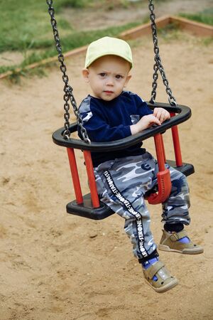 Beautiful boy ride on a childrens swing, 1-2 year oldの写真素材