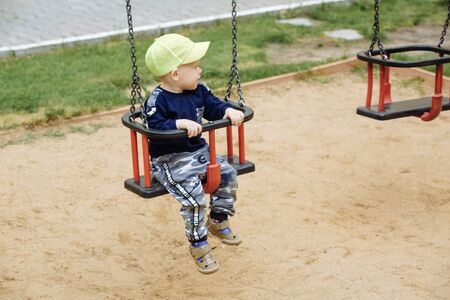 The child is riding on a swing, a playground , 1-2 old yearの写真素材