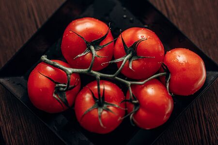 Red tomatoes on black plate. Top viewの写真素材