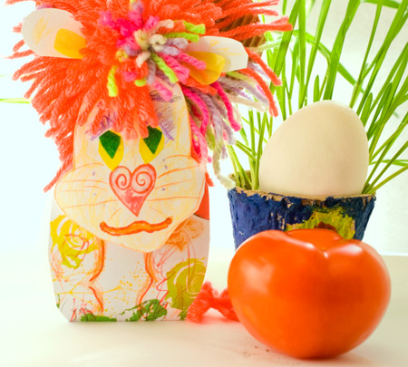 Tomato, egg and greens in a pot near the artificial lion on a light backgroundの写真素材