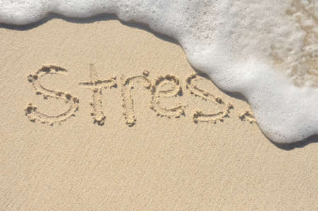 Relieving Stress, the Word Stress Being Washed Away by a Wave on a Beachの写真素材
