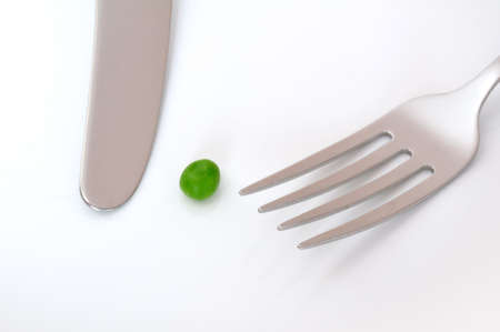 A Single Pea, a Knife, and a Fork on a White Plateの写真素材