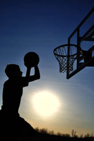 Silhouette of a teen boy going for a dunk