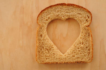 Wheat Bread Slice with Heart on Cutting Boardの写真素材