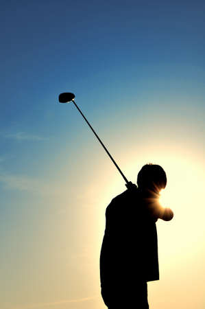 Silhouette of a man swinging a driverの写真素材