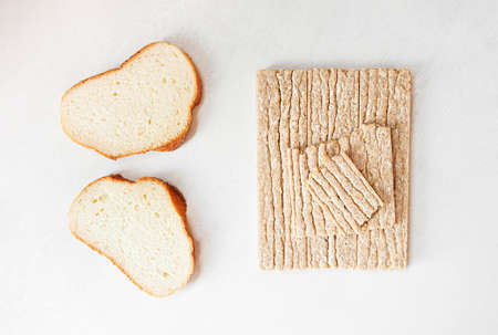 Different types of bread, white yeast bread and healthy crispbread on a white cement table, top viewの写真素材