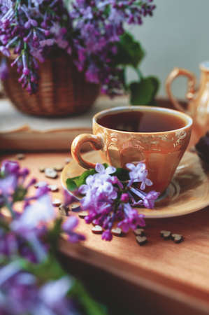 stylish small porcelain gold Cup full of black tea on a gold saucer, on a wooden tray decorated with...