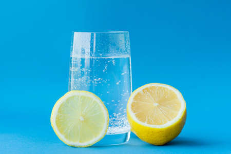 translucent glass of water with gases and bubbles, with a round slice of lemon on a glass and a...