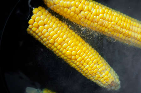 yellow raw corn is cooked in boiling water with bubbles