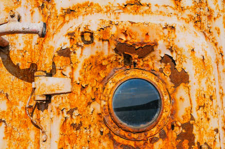 the door and porthole of a very old abandoned completely rusty shipの写真素材