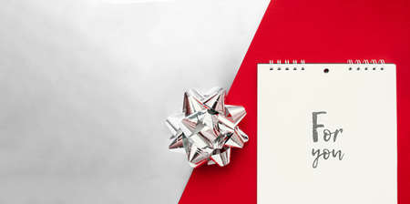 notebook on a spiral with white sheets and black lettering for you and ha silver foil bow on...