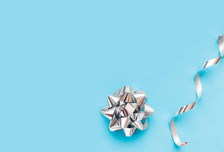 silver foil bow and packing silver ribbon on blue background. Mockup for greetings