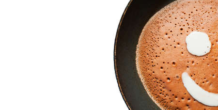Banner with white space for text. A pancake made of liquid chocolate dough with bubbles is fried in...