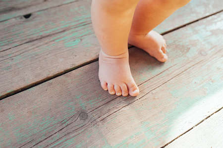 plump bare feet and fingers of a small child on the rough wooden floorの写真素材