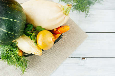 raw vegetables from the garden, zucchini, carrots, green pumpkin, onions, dill and parsley on a...