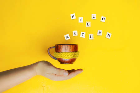 levitation objects, neat hand supports flying wooden mug with yellow knitted warm scarf and words...