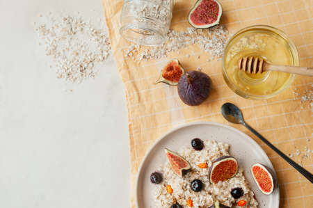 healthy vitamin breakfast, oatmeal porridge, blueberries, fresh figs and sea buckthorn on yellow...