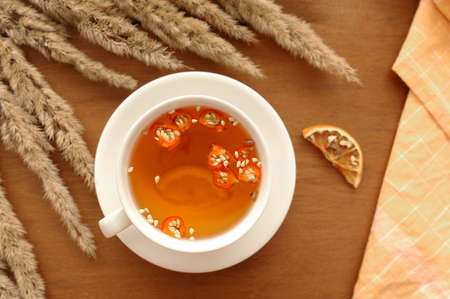 cozy autumn Breakfast with useful tea, honey, cinnamon sticks, lemon, dogrose berries and bouquet of dried flowers and cotton orange napkin for serving, selective focusの写真素材