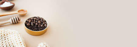 cosmetic banner anti-cellulite products, Coffee scrub in gold jar, honey, cosmetic oil, wooden stick for honey and rough massage glove against pastel beige background, cselective focusの写真素材