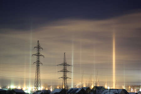 Columns of light from lanterns over a city against the sky in the winterの写真素材