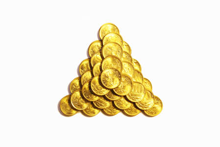 Triangular pyramid from coins of yellow metal on a white backgroundの写真素材