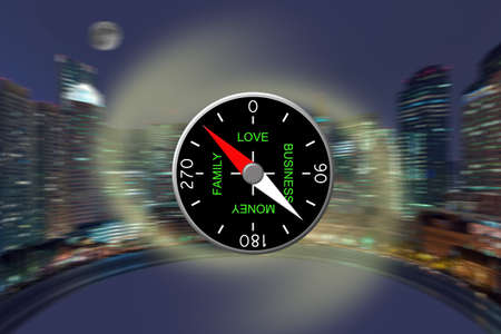 The compass specifying possible life priorities: love, money, a family, business against a night panorama of a cityの写真素材