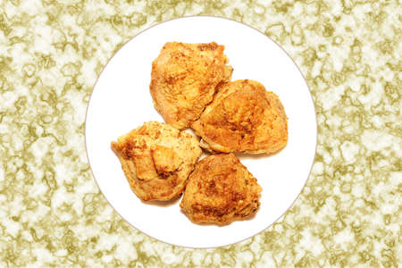 Four portions of roast chicken with spices on a white plateの写真素材