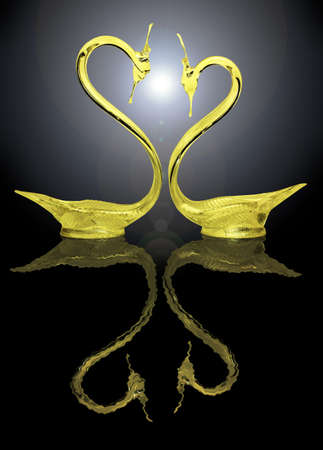 Two gold swans and their reflection on a black backgroundの写真素材