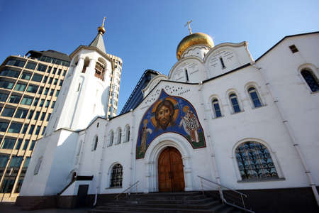 The old Church with a bell tower and a modern building behind itの写真素材