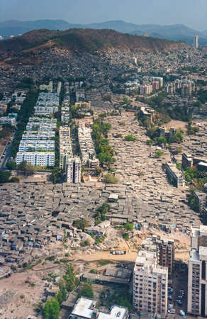 The slums of Mumbai, seen from the air, fill every gap between larger residential buildings and officesの写真素材