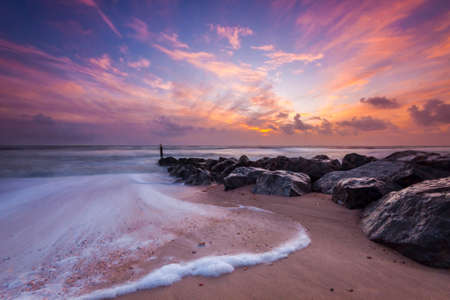 Beautiful sunet on the Dorset coast. Ocean waves batter the sea defencesの写真素材