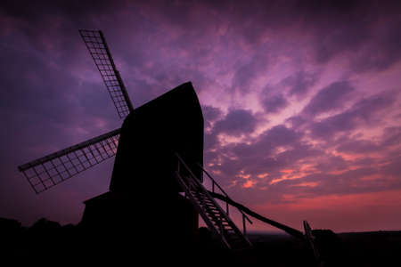 An ancient post mill sits atop of a hill in Buckinghamshire at sunsetの写真素材