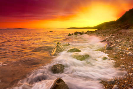 The beach at Osmington at sunset with breaking waves on the shorelineの写真素材
