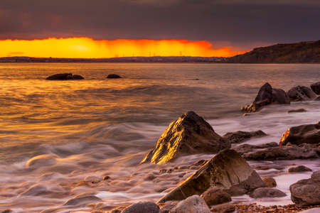 The beach at Osmington at sunset with breaking waves on the shorelineの写真素材