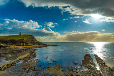 Sunlight illuminates the rocks and pools on the craggy Dorset coastlineの写真素材