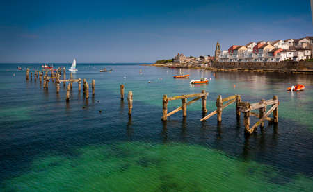 The old pier posts can be seen in the blue-green waters under the new houses perched on the seafrontの写真素材