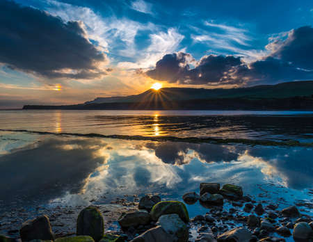 Golden sunlight illuminates the sea rocks and cliffs on the Jurassic Coastline of South Dorsetの写真素材