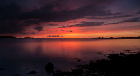 Tranquil waters and orange sun glow over still seas