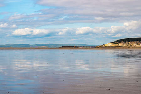 Reflections of the sky can be seen in the wet sands at Weston beachの写真素材
