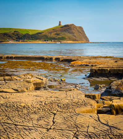Calm waters of Kimmeridge Bay reflect views of Clavell's Tower under blue skiesの写真素材