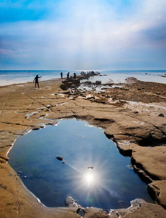 Calm waters of Kimmeridge Bay reflect views of Clavell's Tower under blue skiesの写真素材