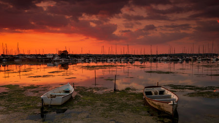 The sun sets over boats in the backwaters of Holes Bay, Poole Harbour at low tideの写真素材