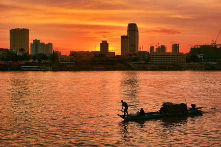 Fisherman boast at sunset at a modern city riversideの写真素材