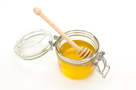 Honey jar with a wooden stick for honey on white background. Concept of healthy food. Honey like superfood. Minimalism style.の写真素材