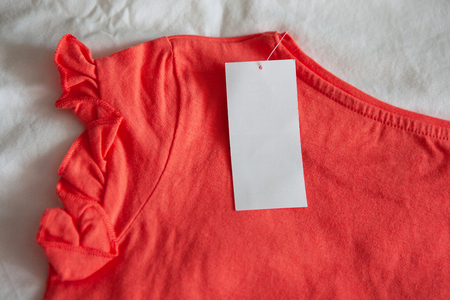 New pink red kid's or women's t-shirt with tag on white background. Concept shopping, summer sales, discounts, organic cotton clothes, recycled clothingの写真素材