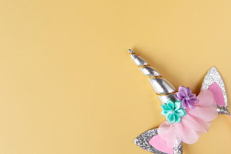Halloween party accessory, rim with ears and unicorn horn. Pastel yellow background, copy space. Holiday flat lay. Minimal style. Horizontal.の写真素材