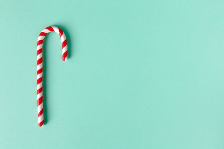 Christmas peppermint candy cane on pastel turquoise background. Festive minimal style flat lay....