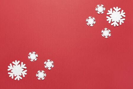 Christmas composition, group of little white felt snowflakes on burgundy red background, copy space. Festive, New Year concept. Horizontal, flat lay. Minimal style. Top view.の写真素材