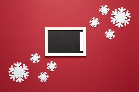 Christmas composition, small chalk board, frame of snowflakes with copy space on dark red background. Blank for postcard layout. Festive, New Year concept. Horizontal, flat lay. Minimal styleの写真素材