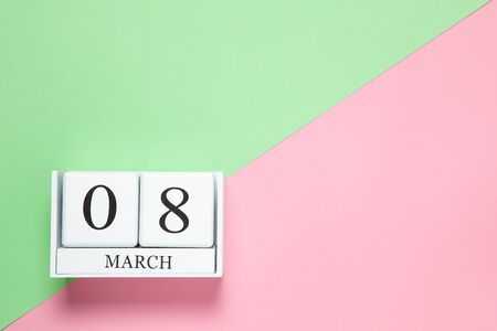 Perpetual calendar with date of March 8 on two-color background pink and green. Flat lay. Top view....